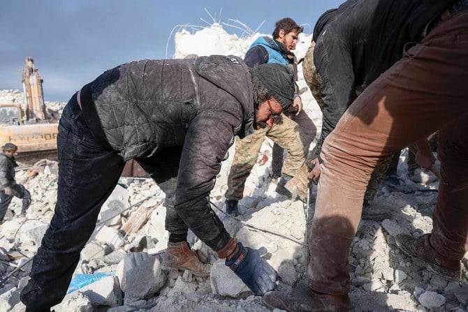 シリアのイドリブ県にあるベスナヤ村で、瓦礫の中に閉じ込められた家族を探し、救助隊の瓦礫撤去を手伝うシリア人男性。（AFP）