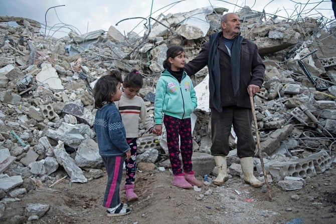 2023年2月7日の大地震の後、 シリア北西ラタキア県の町ジャブレで倒壊した建物のがれきの合間にたたずむ家族 (AFP)