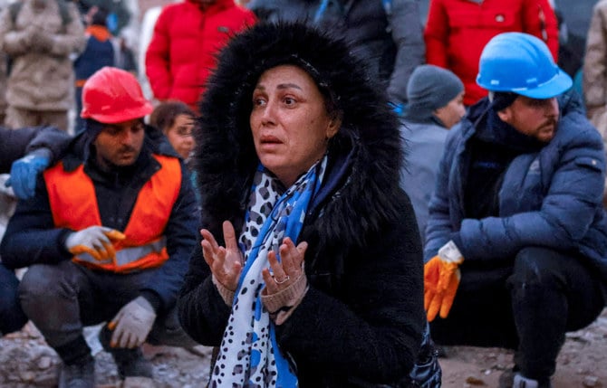 トルコのハタイ県で、地震で倒壊した建物近くで続く救助活動を見守る女性。2023年2月10日（ロイター）