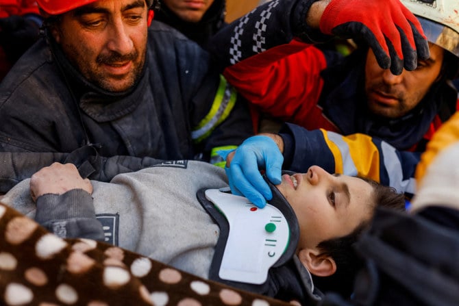 トルコ・シリア地震の6日後、11歳の生存者モハマド・アルカナス君に付添う救急隊員たち。トルコ、ハタイ。（ロイター通信）