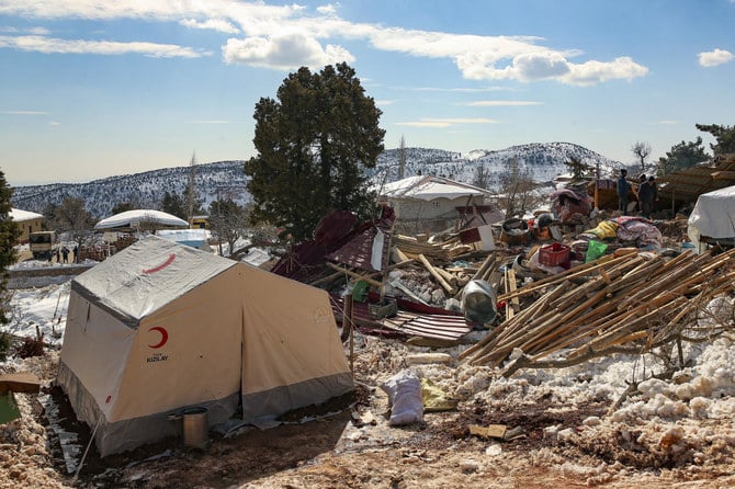 2023年2月15日水曜日、トルコのカフラマンマラシュ県ビュユクナカル村で倒壊した住宅の横を歩く人々。（AP）