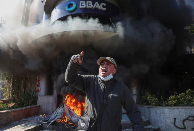 「預金者の抗議」主催の抗議デモ中、火をつけられた銀行の近くで身振りをするデモ参加者。（ロイター）