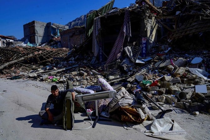 トルコ南部の歴史的な街アンタキヤで倒壊した建物のそばに佇む男性（2023年2月12日）。週のはじめにトルコとシリアの国境付近をM7.8の地震が襲った。（AFP）