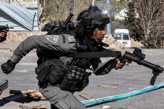 イスラエル当局による家屋の解体に反対するパレスチナ人のゼネラル・ストライキが宣言される中、パレスチナ人との衝突で暴動取締用の銃を持って走るイスラエルの国境警備隊員。(AFP)