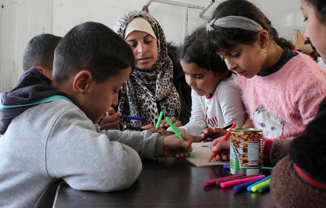 シリアのラタキアで、大地震による被災家族のための避難所となった学校で、3人の子どもの母親（39歳）が子どもたちと一緒に座っている。(ロイター)
