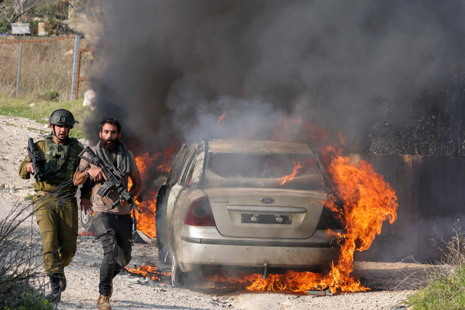車に放火した入植者ら（奥）に向かって投石するパレスチナ人の若者ら。2023年2月25日、ブリン村。（AFP）