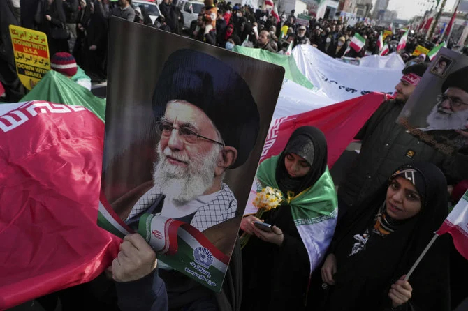 1979年のイスラム革命を記念してテヘランで行われた年次集会で、巨大なイラン国旗とアーヤトッラー・アリー・ハメネイ最高指導者のポスターを掲げたデモ参加者たち。（AP）