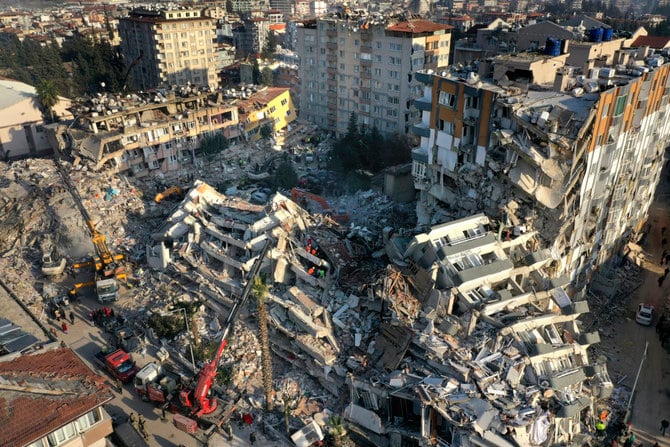 クレーンが倒壊した建物の瓦礫を撤去する中、捜索を行う救助チーム。2023年2月10日、トルコ南東部アンタキヤ。（写真：AP/Hussein Malla）