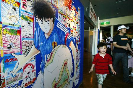 この資料写真は 2002年5月5日に撮影されたもので、東京で催された漫画の展覧会の出入り口にいる、日本の漫画『キャプテン翼』シリーズのキャラクター大空翼(左)が写っている。(AFP)