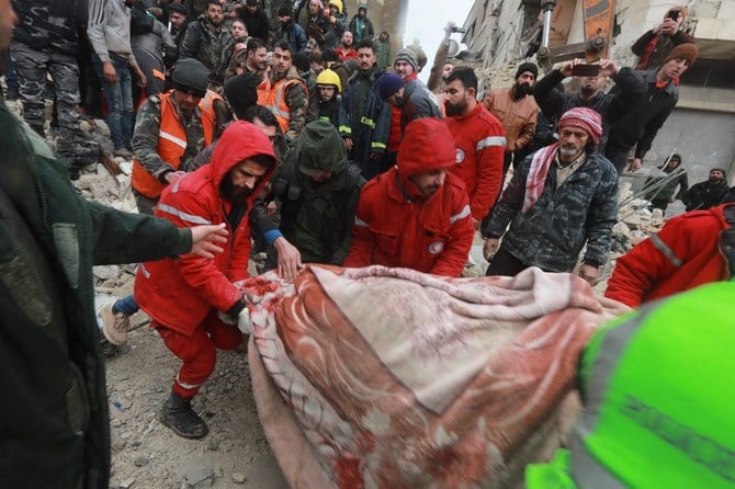 シリア政府支配下のシリア中央部の都市、ハマで発生した地震の後、瓦礫の中から救出された犠牲者を運ぶシリアの救助隊。2月（AFP）