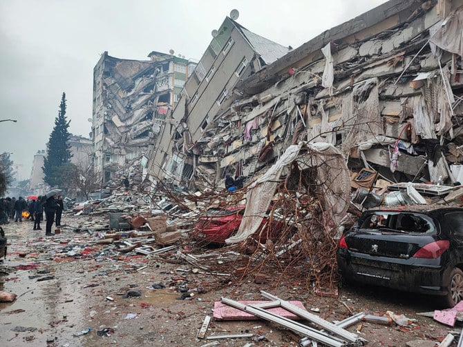 2023年2月6日、トルコのカフラマンマラシュで地震が発生した後、倒壊した建物の前に立つ人々。（ロイター）