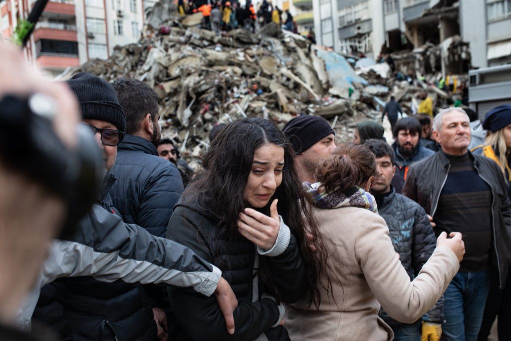 トルコ南東部でマグニチュード7.8の地震が発生した後、倒壊した建物の瓦礫の中で生存者を捜索する救助隊に応答する女性。2023年2月6日、アダナ。（AFP）