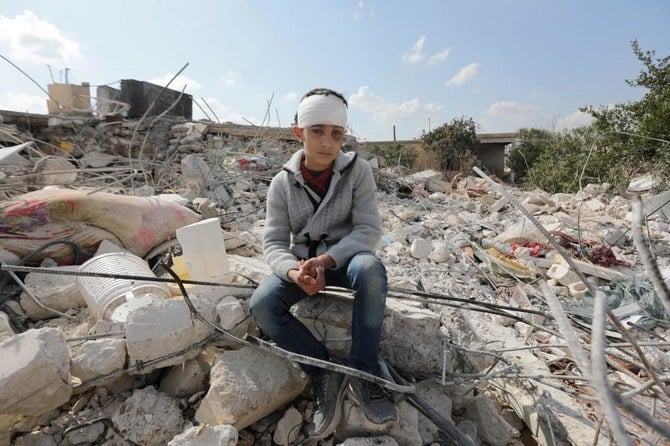 トルコとシリアを襲った地震で家族を亡くし、アレッポの町ジャンダリスにある実家の瓦礫の中に座るシリアの少年。(ファイル/AFP)