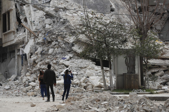 最近の地震で倒壊したシリア・アレッポの建物のそばにたたずむ人々（2023年2月27日）。（AP）