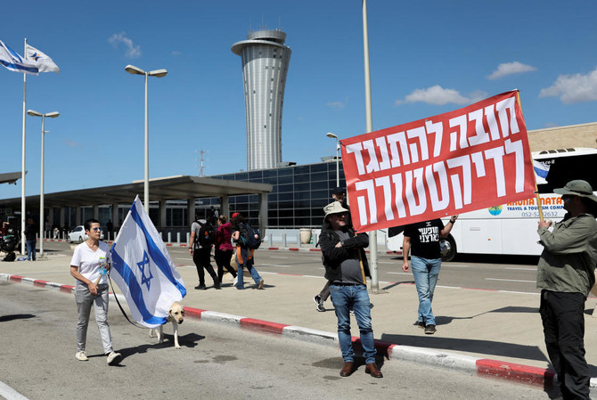 イスラエルの国旗を振る抗議者たち。イスラエルの主要国際空港に集まり、出発ロビーに通じる幹線道路を車で塞いだ。（ロイター）