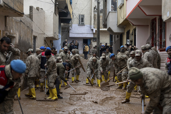 2023年3月16日、トルコ、シャンルウルファ県の大雨による洪水で、泥に覆われた道路を清掃する兵士と警察官。（ウグル・イルディリム / DIA、AP経由）
