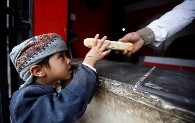 2018年11月9日、イエメン、サヌアの慈善ベーカリー「マーシー・リリーフ」にて、少年にパンを渡す労働者。（ロイター通信）