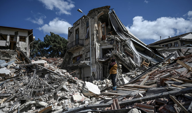 2023 年3月6日、トルコのハタイで倒壊した建物の瓦礫の中に立ち尽くす女性。(AFP)