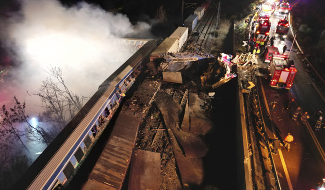 ギリシャのラリサ近郊の列車衝突現場で救助隊員が作業する中、列車から煙が立ち上っている。2023年3月1日（水）未明撮影。（AP）