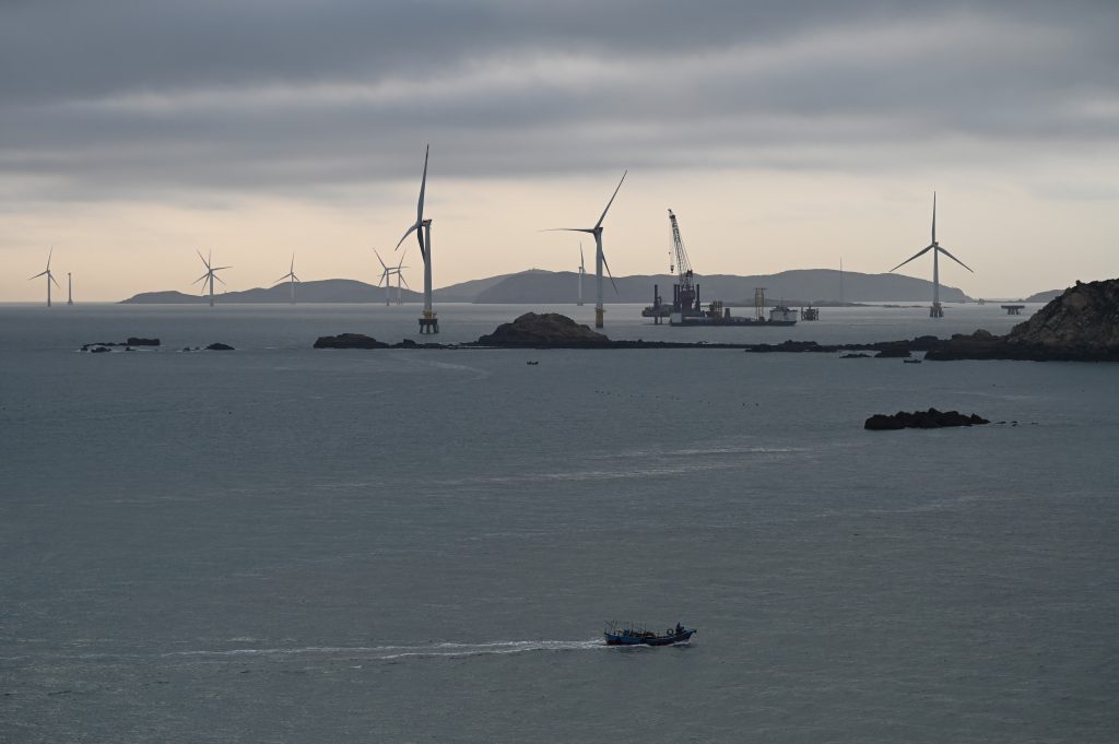 台湾の対岸にある平潭島の北側で、風力発電機の付近を航行する漁船=2023年4月10日、中国南東部・福建省(AFP)