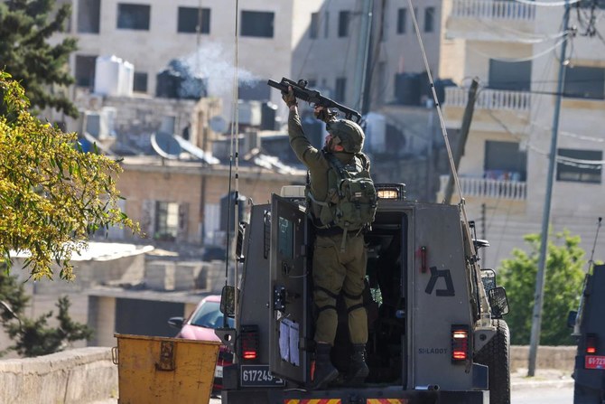 イスラエル統治下のヨルダン川西岸地区にあるナブルス市にて、イスラエル軍による襲撃を受け、投射物を発射するイスラエル軍兵士。（AFP）