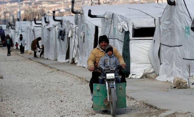 バイクに乗ってテントの間を移動するシリア難民の男性とその息子。2021年3月5日、レバノン東部ベッカー高原のバル・エリアスにある難民キャンプ。（写真：AP）