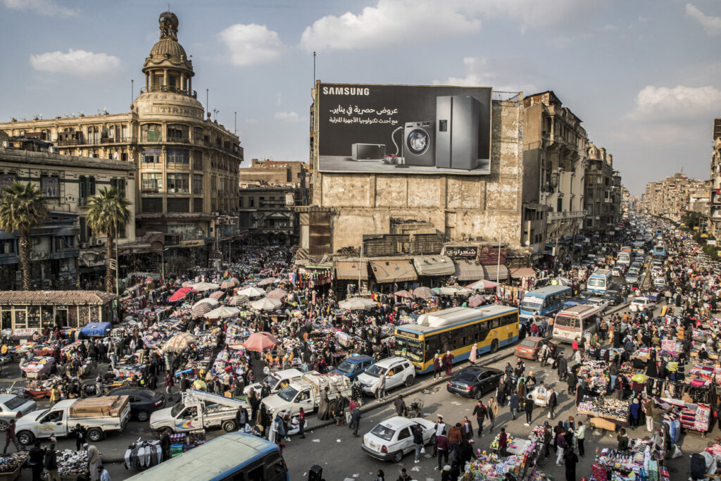 エジプトの首都カイロのアッタバ中心地区で、露天商や物売りに混じって渋滞に巻き込まれている車。2021年2月22日に撮影。（AFP）