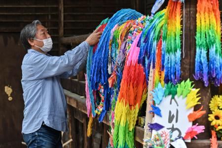 2023年5月14日に撮影されたこの写真には、広島の近くにある宮島の仏教寺院大聖院にて、お焚き上げを前に数千羽の折り鶴を準備している、平和的な活動をする団体「なごみプロジェクト」のメンバーである、テシマヒロシ氏が写っている。（AFP） 