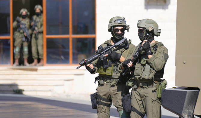 ヨルダン川西岸の村カフィンで、銃撃犯と思われる人物を捜索するイスラエル軍兵士。(AP)