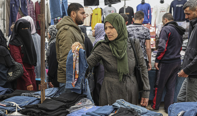 ガザ市の市場で衣類を物色するパレスチナ人女性。輸出入税の増税で業者の不満が高まっている。（AFP）