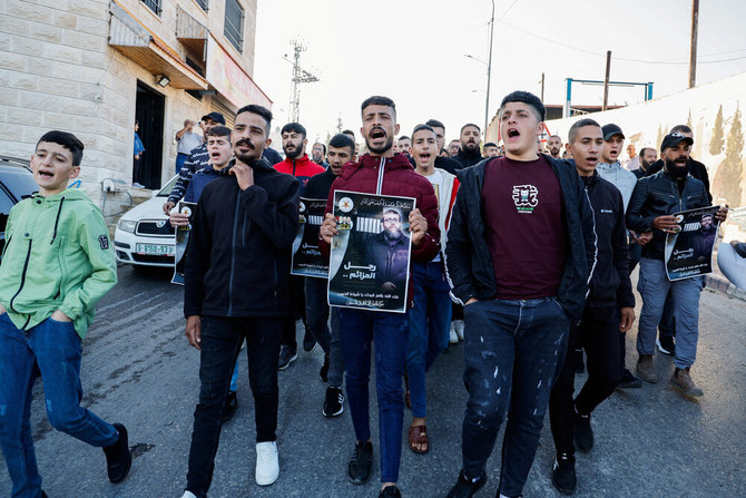 5 月 2 日、イスラエル占領下のヨルダン川西岸のジェニン近郊で、イスラエルの刑務所でハンガーストライキ中のパレスチナ人ハデル・アドナン氏の死亡に対し、ポスターを掲げて抗議するパレスチナ人たち。（ロイター）