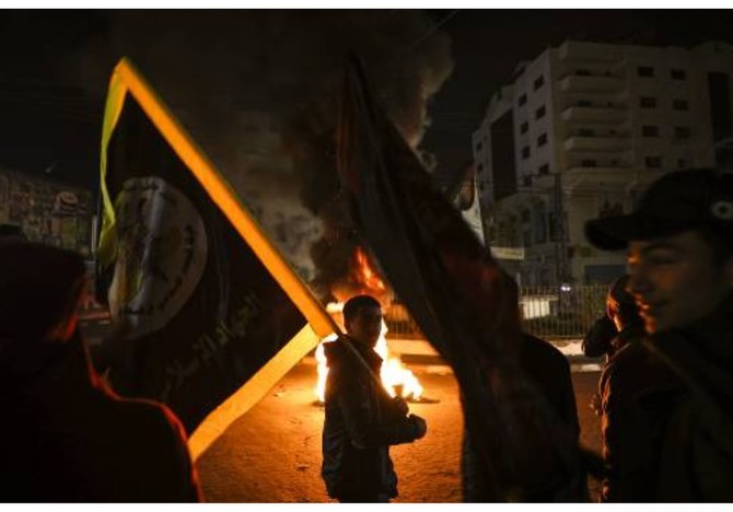 イスラエルとガザの国境付近、ガザ市の東部でのデモ中に燃えるタイヤの前を旗を手に通過するパレスチナの若者（2023年2月26日）（AFP/資料写真）