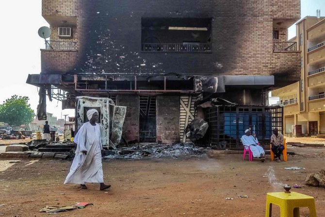 2023年5月24日、ハルツーム南部で焼け落ちた銀行支店の前を歩く男性。（AFP）