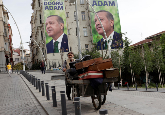 イスタンブールで行われた大統領・議会選挙の第1回投票後、トルコのタイップ・エルドアン大統領の選挙キャンペーンポスターを背景に、路を歩く行商人。（ファイル写真／ロイター通信)