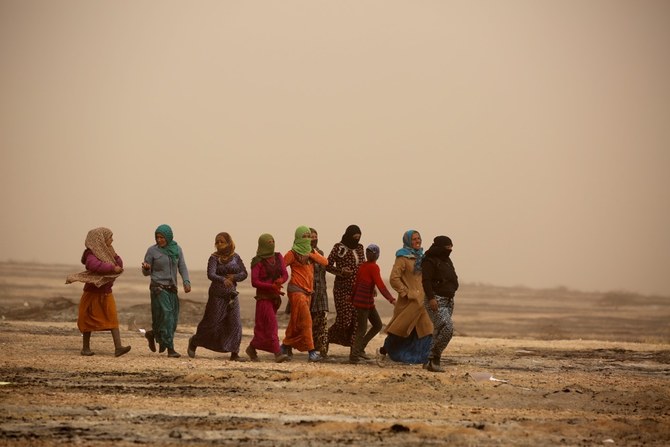アイン・イッサ村内の仮設難民キャンプ近傍で、砂嵐の中を歩くシリア人女性。（AFP / 資料写真）