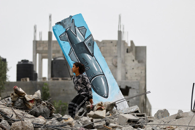 ガザ地区中心部のデイル・アル・バラで、イスラエルによって破壊された家屋にパレスチナ人アーティストが描いたグラフィティの側を通り過ぎるパレスチナ人の少女。（ロイター）