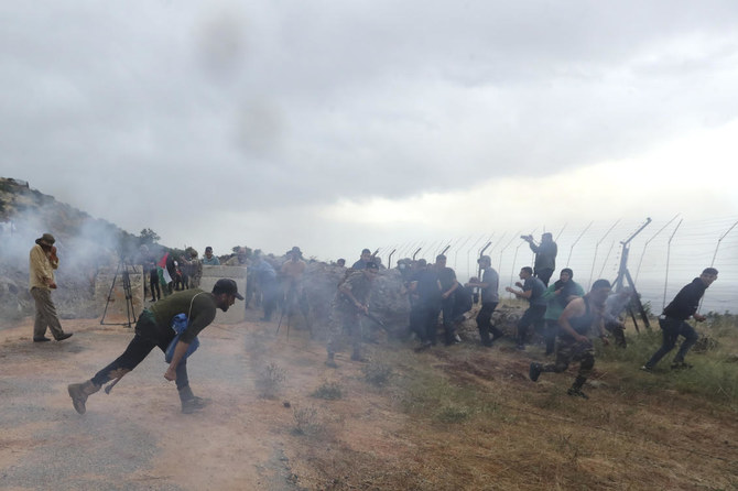 2023年6月9日、レバノン南部の国境の村クファルチョウバで、イスラエル軍が催涙ガスを発射した後、身をかがめるレバノンの兵士、抗議者、ジャーナリスト。（AP通信）