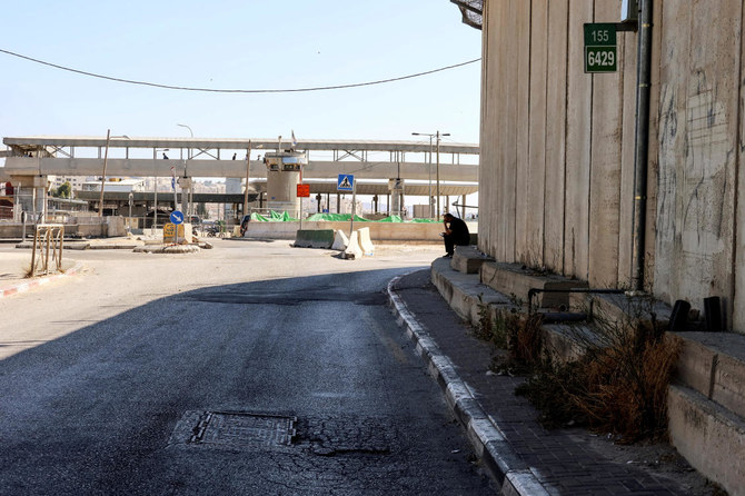 ヨルダン川西岸地区のカランディア検問所のそばに座る男性。イスラエル警察によると、同検問所ではこれより前、パレスチナ人とされる人物が発砲し警備員を負傷させた後に射殺された。（ロイター）
