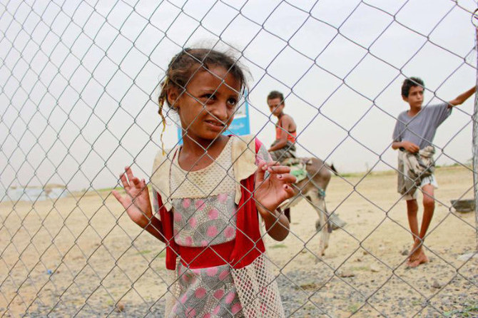 イエメンのハジャ県にある国内避難民キャンプで、閉鎖された診療所のフェンス越しに様子をうかがうイエメン人少女。（ロイター）