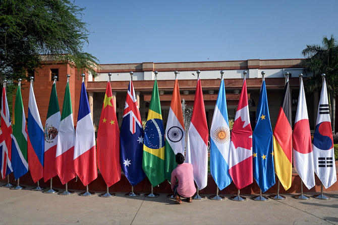 2023年3月2日、インドのニューデリーで開催されたG20外相会合で、参加国の国旗を並べる男性。（AFP）