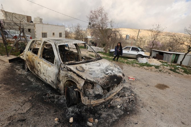 イスラエル人入植者らによって放火されたとされる黒焦げの車のそばを通り過ぎるパレスチナ人の少女。2023年1月、ナブルスの南にあるジャルド村。（AFP）