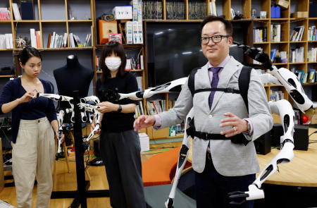 2023年6月22日、東京大学の研究室でのデモンストレーション中に東京大学の稲見昌彦氏が着用する装着可能型ロボットアーム「自在肢（JIZAI ARMS）」と同期するロボットアームの制御ユニットを制御する職員。（ロイター）