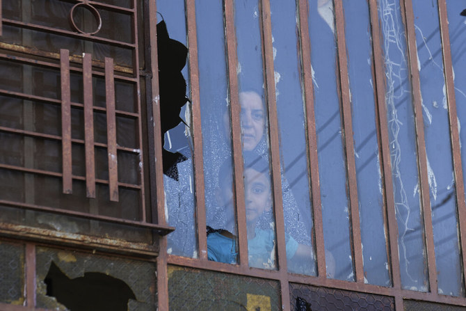 イスラエル人入植者が壊したとされる割れた窓の向こうに見える自宅内のパレスチナ人。2023年6月21日、ヨルダン川西岸地区の村A Laban Al-Sharkiyeh にて。（AP通信）