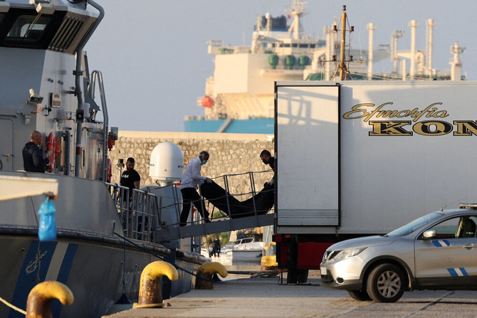 2023年6月15日、カラマタ港のヘレニック沿岸警備隊の船上で、ギリシャ沖の外洋でボートが転覆して亡くなった移民の遺体袋を移動する作業員(ロイター)