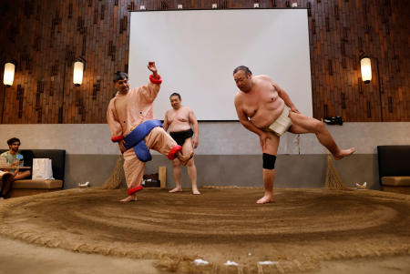 2023年6月30日、東京の「横綱とんかつどすこい田中」の土俵で、力士の衣装を着たメキシコ人観光客と相撲を実演する元力士の琴鳳(40)と鳥羽の山(45)。(ロイター)