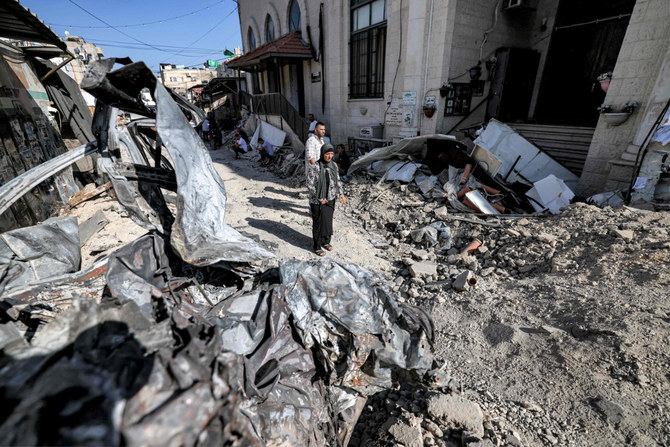 占領下のヨルダン川西岸地区の都市ジェニンのモスクの外で、破壊された自動車の残骸と瓦礫の傍に立つ人々。2023年7月5日。（AFP）