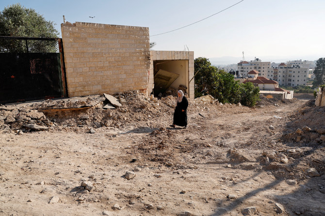 2023年7月5日、イスラエル占領下のヨルダン川西岸地区のジェニンにて、イスラエルによる2日間にわたる襲撃後、破壊された自宅近くを歩くパレスチナ人女性。（ロイター）