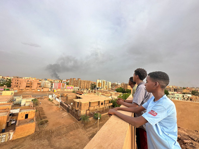 2023年7月4日、スーダンのオムドゥルマンで、軍と準軍事組織・即応支援部隊との衝突の中、煙が上がるのを眺める人々。（ロイター）  