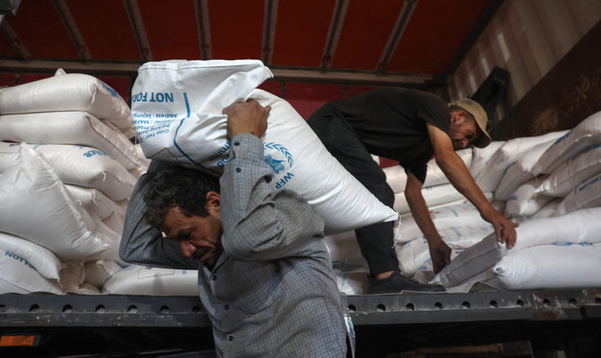 2023年7月10日、トルコとの国境にあるバブ・アル・ハワ検問所近くの倉庫で、支援物資の袋を降ろす作業員。（AFP）