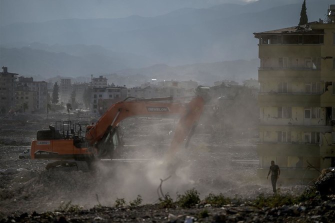 マグニチュード7.8の地震とその余震がトルコ南東部の山岳地帯に壊滅的な被害をもたらした5ヶ月後、ショベルカーが倒壊した建物の瓦礫を片付けるのを眺める男性。2023年7月9日、アンタキヤ。（AFP）